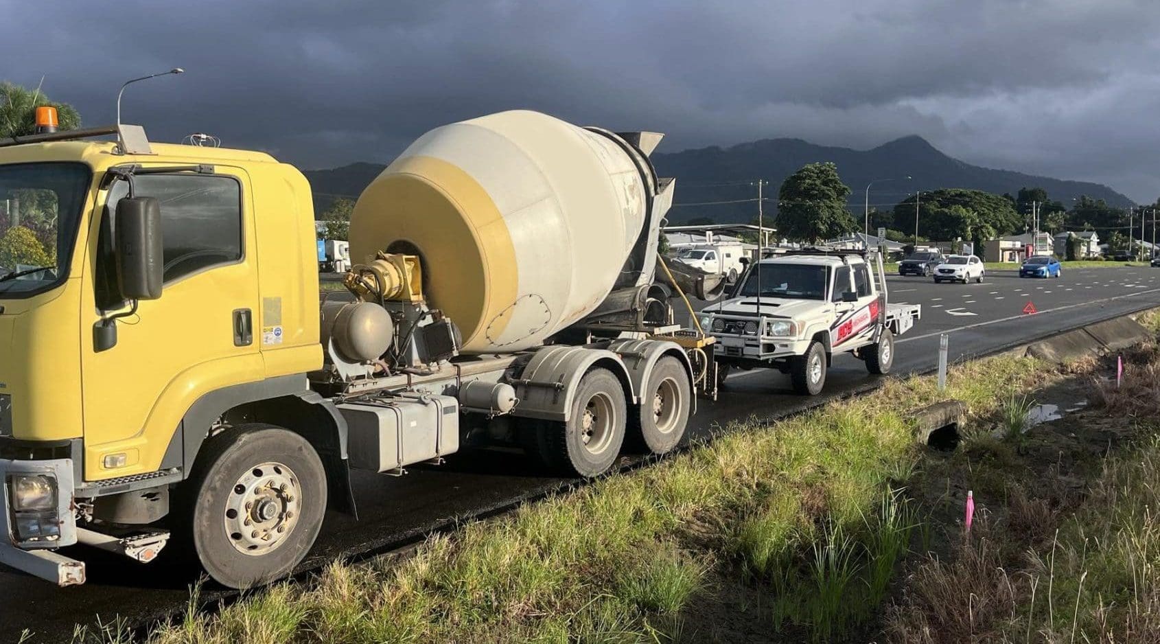 Truck broken down on the roadside with mobile mechanics on the scene helping out.