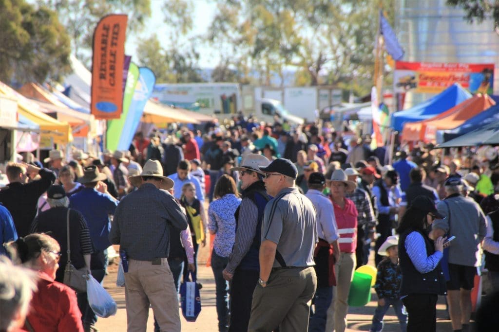 Visitors walking through crowded aisles at FarmFest 2025 in Toowoomba, surrounded by exhibition stands and colourful banners.